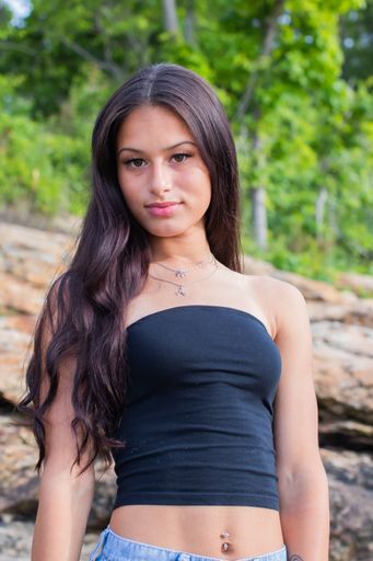 A vertical selective focus of an attractive Hispanic female with long hair on background of rocks