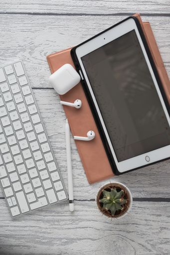vertical tabletop shot of a white bluetooth keyboard, working home office at a tablet computer, germany, white wooden background