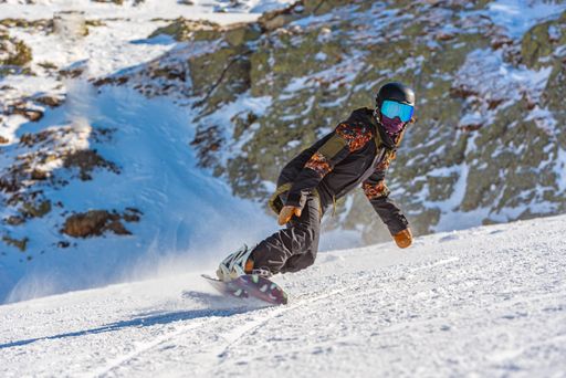 A closeup of a female snowboarder in motion on a snowboard in a mountain