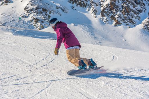 Arcalis, Andorra: 2021 January 16 : Young woman snowboarder in motion on snowboard in mountains