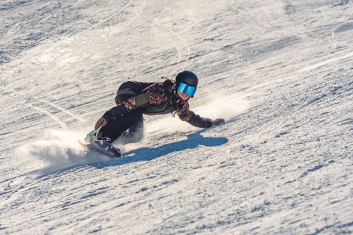 A closeup of a female snowboarder in motion on a snowboard in a mountain