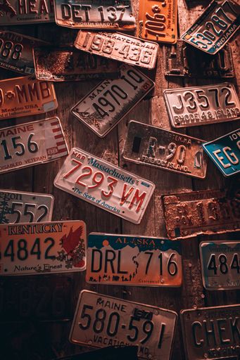 A vertical shot of a wooden wall full of license plates