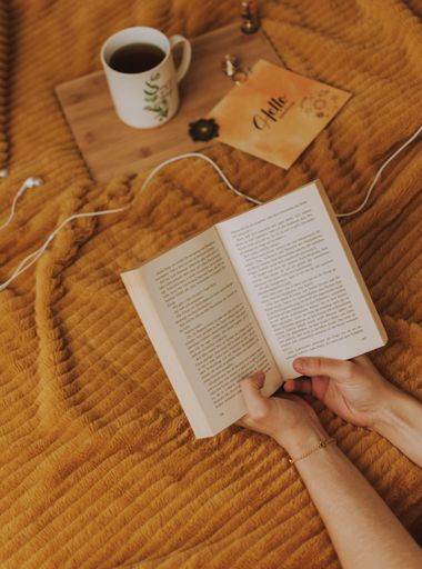 A cup of coffee, poster and a book on a dark orange smooth surface