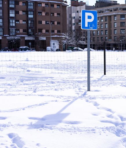 A parking sign in a park covered in snow