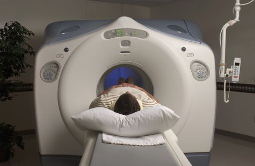 A person lying in an MRI scanner under the lights in a hospital