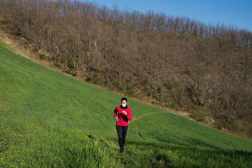 A young Caucasian female running in a park wearing a protective medical mask during Coronavirus pandemic