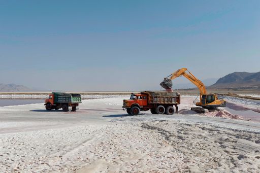 A landscape shot of the process of loading salt onto a truck at Maharlu lake in Shiraz, Iran
