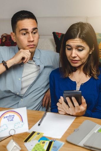 A vertical shot of a surprised young couple calculating bills and taxes - the concept of planning family budget