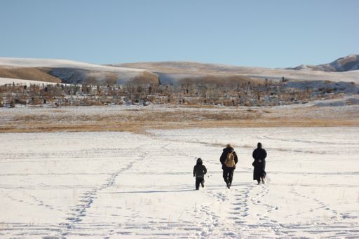 A beautiful view of people walking in the field covered in snow, and mountains in the background