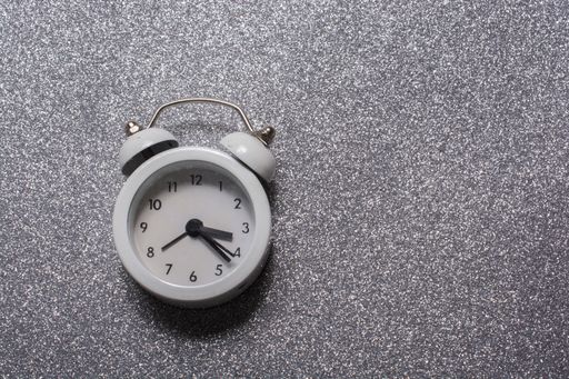 A top view of a white alarm clock on a concrete surface