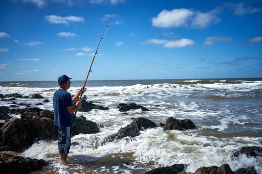 A person wearing sunglasses while fishing by a sea captured on a sunny day