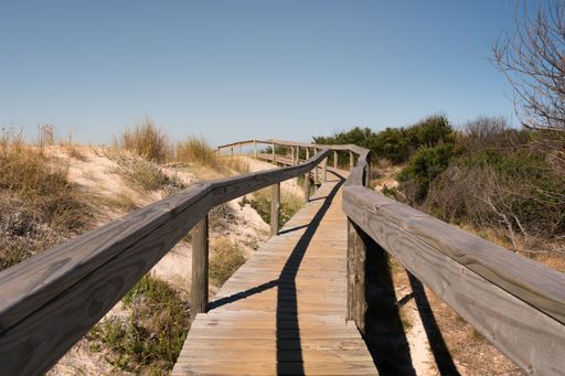 A wooden narrow pathway with a handrail in Santa Lucia del Este Canelones beach in uruguay