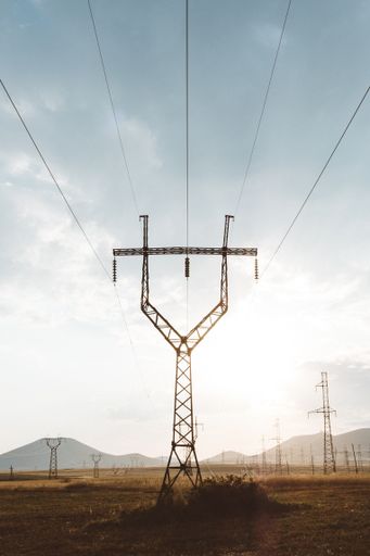 A vertical shot of an electric post with metal railings on top under a cloudy sky