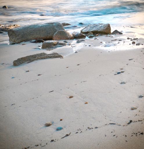 A beach covered in rocks surrounded by the sea with long exposure under the sunlight