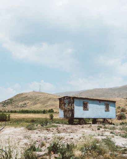 A wide angle shot of an old metal wagon on a mountain under a cloudy sky
