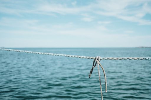 A closeup shot of a gray rope near the ocean under a cloudy sky during daytime