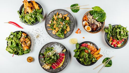 A closeup of a plate of sushi and tempura with fresh vegetables on the white table