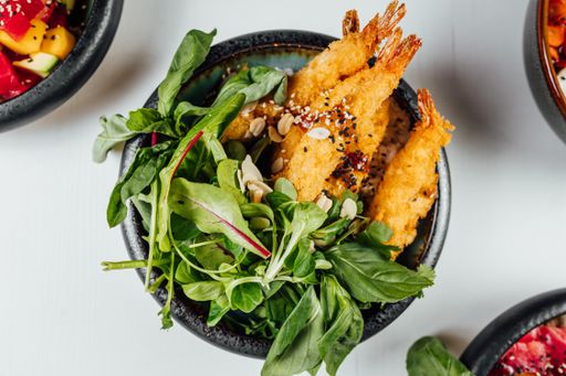 A closeup of a plate of tempura with fresh vegetables on the white table