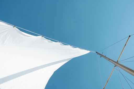 A low angle shot of a white sail on boat mast under clear sky during daytime