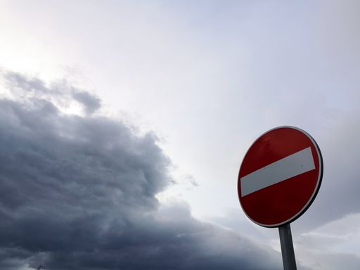 A low angle shot of a round stop sign under a gray cloudy sky