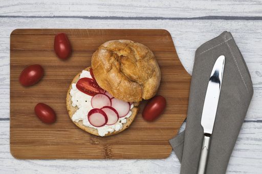 fine roll, bun with cream cheese, radish and tomatoes on a wooden board, white wooden background, germany