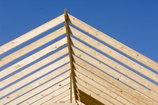 A low angle view of a lumber construction under a blue sky and sunlight at daytime