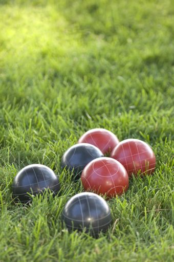 A vertical picture of colourful bocce balls on the lawn under the sunlight with a blurred background