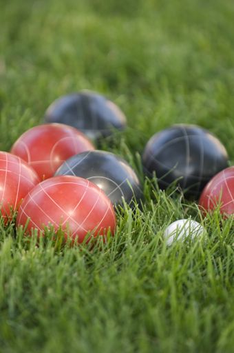 A vertical picture of colourful bocce balls on the lawn under the sunlight with a blurred background