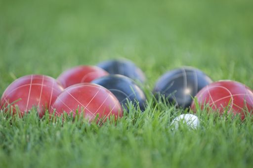 A picture of colourful bocce balls on the lawn under the sunlight with a blurry background