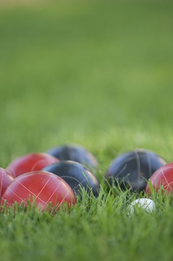A vertical picture of colourful bocce balls on the lawn under the sunlight with a blurred background