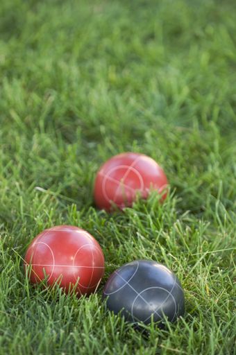 A vertical picture of colourful bocce balls on the lawn under the sunlight with a blurred background