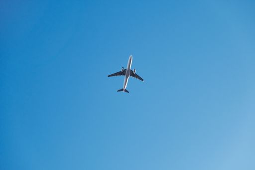 A low angle shot of an airplane flying under a blue sky and sunlight