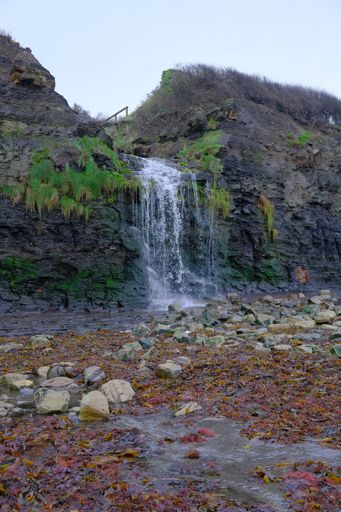 A vertical shot of a small waterfall during the daytime