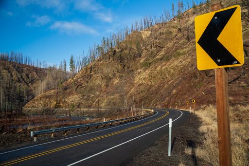 A view of a road with a sharp curve ahead road sign.