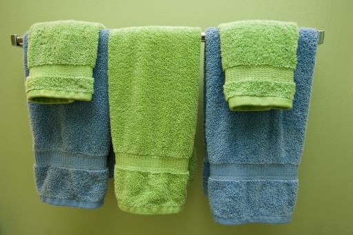 Three colourful towels on the hanger on the green wall under the lights