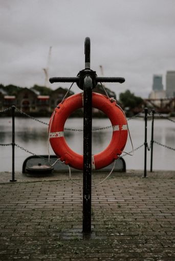 A closeup shot of a lifebuoy ring in front of the water and a city