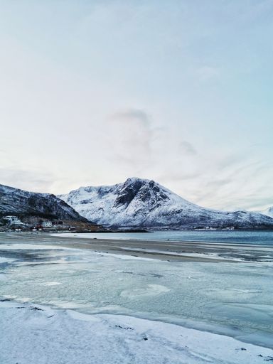 A vertical shot of mountains on the coast in Kvaloya, Tromso, Norway