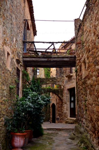 A vertical shot of an alleyway with stone houses in the street of Pals, Girona, Spain