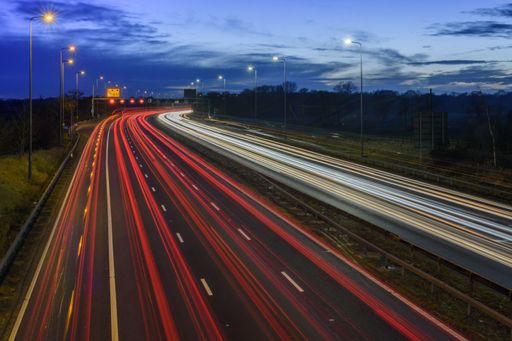 Speeding traffic on M42 motorway during evening rush hour leaves light trails and streaks due to slow shutter speed and long exposure photography.