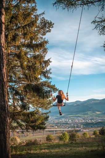 A vertical shot of a young European girl on a tree swing in Ruzomberok Slovakia, Europe