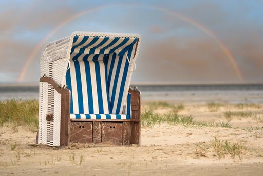 A closeup shot of a beach chair at the coastline on rainbow background