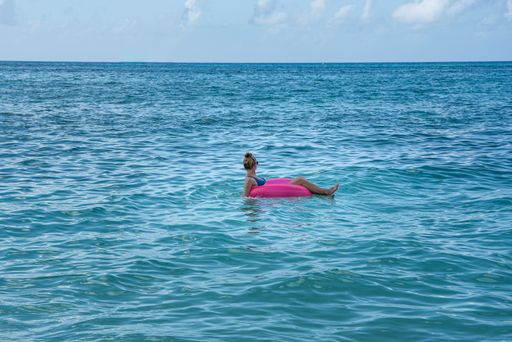 A female wearing a bikini in a sea in a pink float
