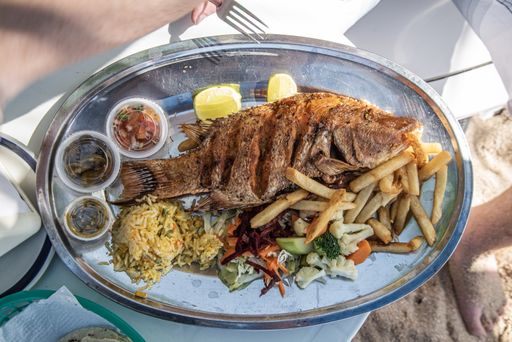 A high angle shot of a delicious fried fish with french fries and sauces on the side