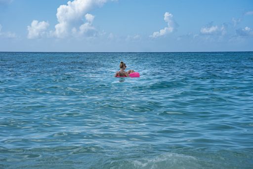 A female wearing a bikini in a sea in a pink float