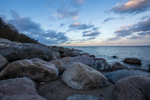 A beautiful shot of a rocky shore on background of the cloudy sky above the sea