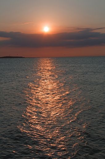 A vertical shot of the ocean under a darkening sky during a sunset