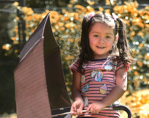 A cute smiling Caucasian little girl holding an umbrella on a sunny day