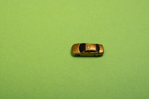 A closeup of a golden-colored small toy car on a green surface - space for text