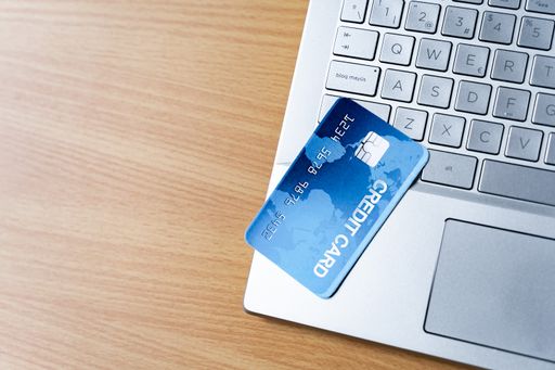 A top view of a credit card on a laptop in background of a wooden surface for a copy space