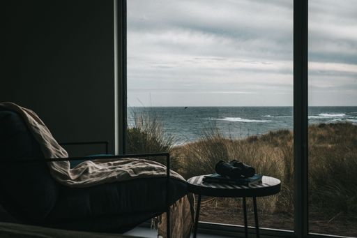 A view of a seascape under a cloudy sky through a glass window.